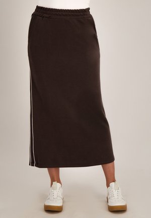 Bruine enkellange rok met zijstreep, elastische tailleband, zakken, gedragen met witte sneakers.