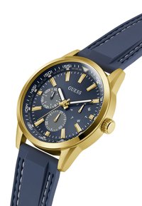 Goldfarbene Uhr mit einem navyblauen Gummiband. Verfügt über ein rundes navyblaues Zifferblatt mit silbernen Akzenten, leuchtenden Stundenmarkierungen und zwei Hilfszifferblättern.