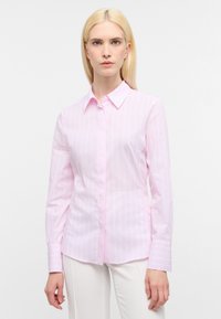 Camicia a maniche lunghe di un delicato rosa pallido, con strisce bianche verticali, colletto a polo e taschino sul petto. Tessuto liscio e leggero.