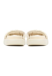 Des sandales à glissière beige clair avec une sangle rembourrée et texturée, et une semelle plate et robuste. Le design présente une finition lisse et des bords arrondis.