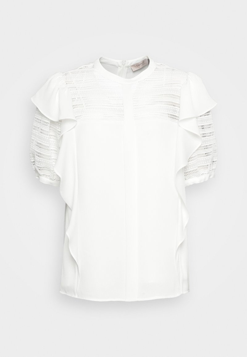 Blusa bianca con maniche corte a sbuffo, caratterizzata da dettagli simili a pizzo nella parte superiore e accenti arricciati lungo i lati.