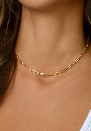 Collar de cadena de oro con eslabones ovalados alargados e interconectados de textura suave, descansando sobre un tono de piel neutro.