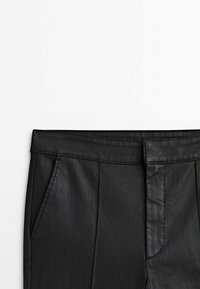 Pantaloni in ecopelle nera con vita, passanti per la cintura, dettagli delle cuciture frontali e tasche laterali su sfondo bianco.