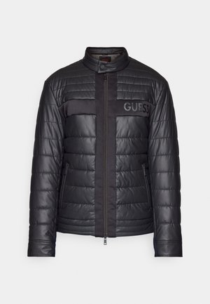 Chaqueta de plumas negra con textura acolchada, cuello alto, cremallera frontal y acento de logo en el pecho. Presenta un panel de tela suave en la parte delantera.