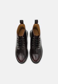 Braune Lederstiefeletten mit glänzender Oberfläche, schwarzen Schnürsenkeln, runder Zehenpartie, kontrastierenden Nähten und Heel-Tab für ein einfaches Anziehen.
