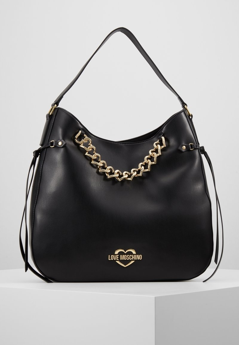 Sac à main Love Moschino en cuir noir avec détail chaîne dorée et logo, doté d'une seule bandoulière et de pompons latéraux.
