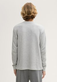 Hellgrauer, langärmeliger, gerippter Pullover mit rundem Ausschnitt und gerippten Bündchen, der einen entspannten Schnitt und einen geraden Saum aufweist.