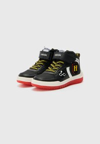 Black high-top sneakers with yellow laces and rubber soles. Features a white lightning bolt and a Hogwarts shield patch on the side.