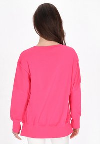 Felpa con retro in fleece, maniche lunghe, di un vivo colore rosa, con vestibilità morbida, spalle scese e polsini e orlo a coste.