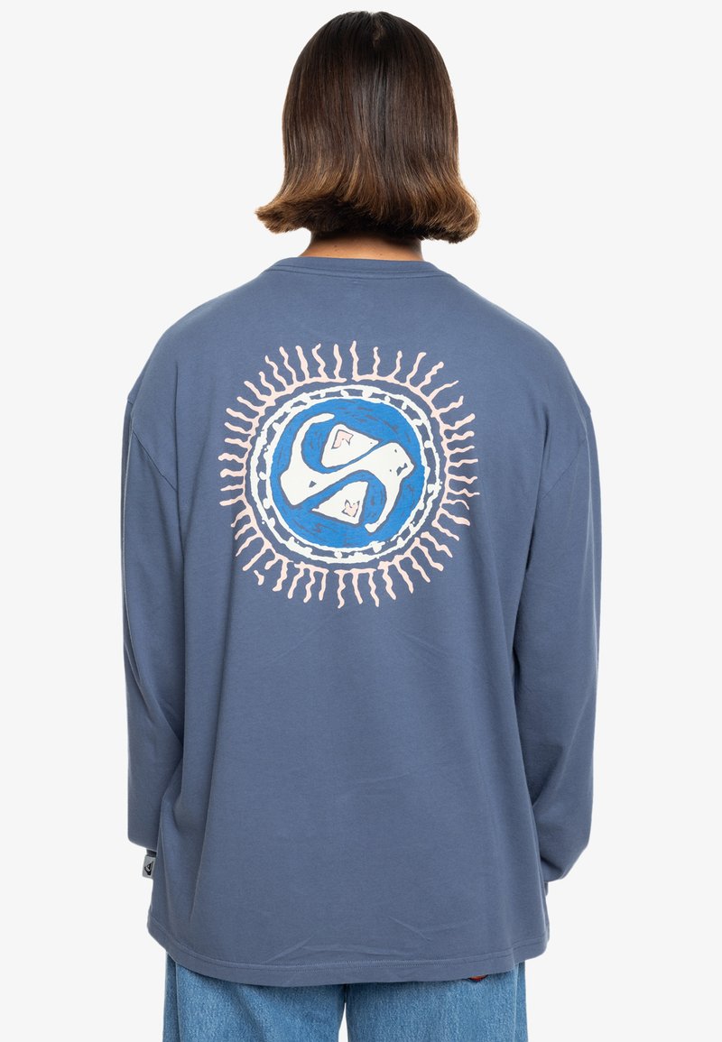 Niebieska bawełniana koszula z długim rękawem, z białym i niebieskim okrągłym graficznym wzorem z promieniami na plecach. Luźny krój, prążkowany dekolt, swobodne rękawy.