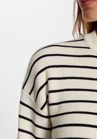 Cremfarbener, gerippter Strickpullover mit schwarzen Horizontalstreifen und einem hohen Kragen. Verfügt über eine lässige Passform und besteht aus weichem, strukturiertem Stoff.