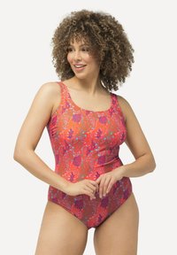 Yhden palan uimapuku kirkkaassa punaisessa, jossa on kukkakuviot violetissa ja sinisessä. Varustettu leveillä olkainilla ja muotoon ommellulla siluetilla.