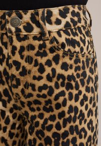 Traperice s leopard uzorkom u bež i crnoj boji, s metalnim kopčanjem i standardnim džepovima.