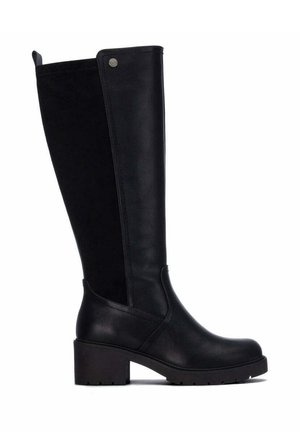 Bota negra hasta la rodilla con tacón bloque, puntera redondeada, panel frontal de cuero liso, panel trasero de ante y pequeño detalle metálico cerca de la parte superior.