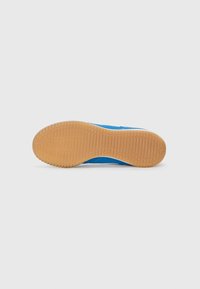 Suela de zapato deportivo azul con patrón de goma texturizada, que presenta ranuras horizontales y verticales para tracción y agarre.