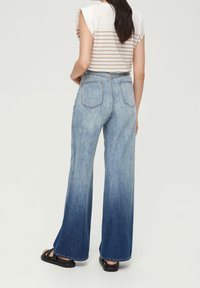 Světle modré džíny s vysokým pasem a rozšířenými nohavicemi, s postupným přechodem od světlého po tmavý denim a dvěma zadními kapsami.