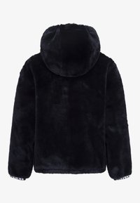 Schwarze Kunstfelljacke mit Kapuze, langen Ärmeln und elastischen Bündchen. Sie hat eine weiche Textur und ein Markenetikett am Saum.