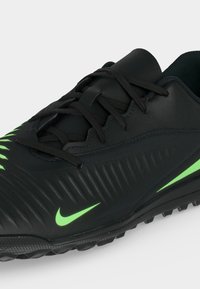 Μαύρο αθλητικό παπούτσι Nike με λογότυπα Swoosh σε νέον πράσινο, υφή στο πλάι και μαύρα κορδόνια σε λευκό φόντο.