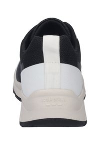 Black and white sneaker with textured fabric upper, contrasting smooth rear panel, thick sole, and brand logo embossed on the heel.
