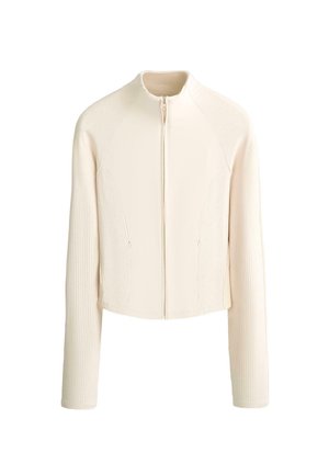 Veste à manches longues de couleur crème avec texture côtelée sur les manches et les côtés, fermeture éclair à l'avant, et col court.