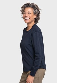 Marineblauseshirt mit Rundhalsausschnitt und gerippten Bündchen, kombiniert mit hellbeigen Hosen; glattes Baumwollgewebe, lässige Passform.