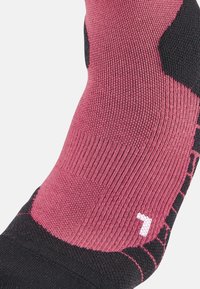 Calzino rosa e nero con texture rigata, dotato di una sezione imbottita e del numero "7" bianco sul lato.