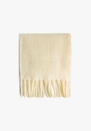 Couverture en laine de couleur crème avec une texture lisse et des bords frangés, pliée soigneusement, mettant en valeur la simplicité du design et des couleurs.