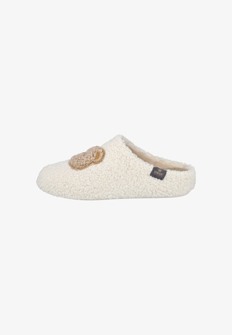 Zapatilla peluda de color crema con una decoración de cara de oso marrón en la parte superior, estilo de deslizar, y una pequeña etiqueta negra de "Comfort" en el costado.