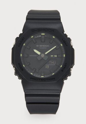 Reloj G-SHOCK negro con una pantalla digital, correa de goma, acentos luminiscentes y una caja resistente. Resistente al agua hasta 20 bares.