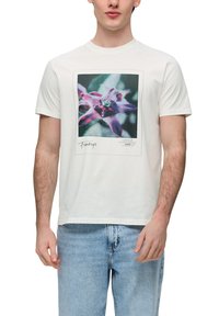 Witte katoenen T-shirt met een rechthoekige bloemenafbeelding in paars, groen en zwart, met tekst onder de afbeelding. Klassiek ontwerp met ronde hals.