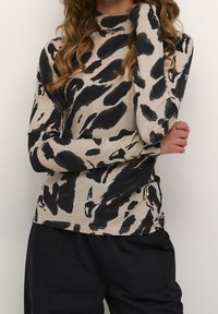 Chemise à manches longues beige avec un motif abstrait noir, présentant un col montant, un design ajusté et un tissu doux et extensible.