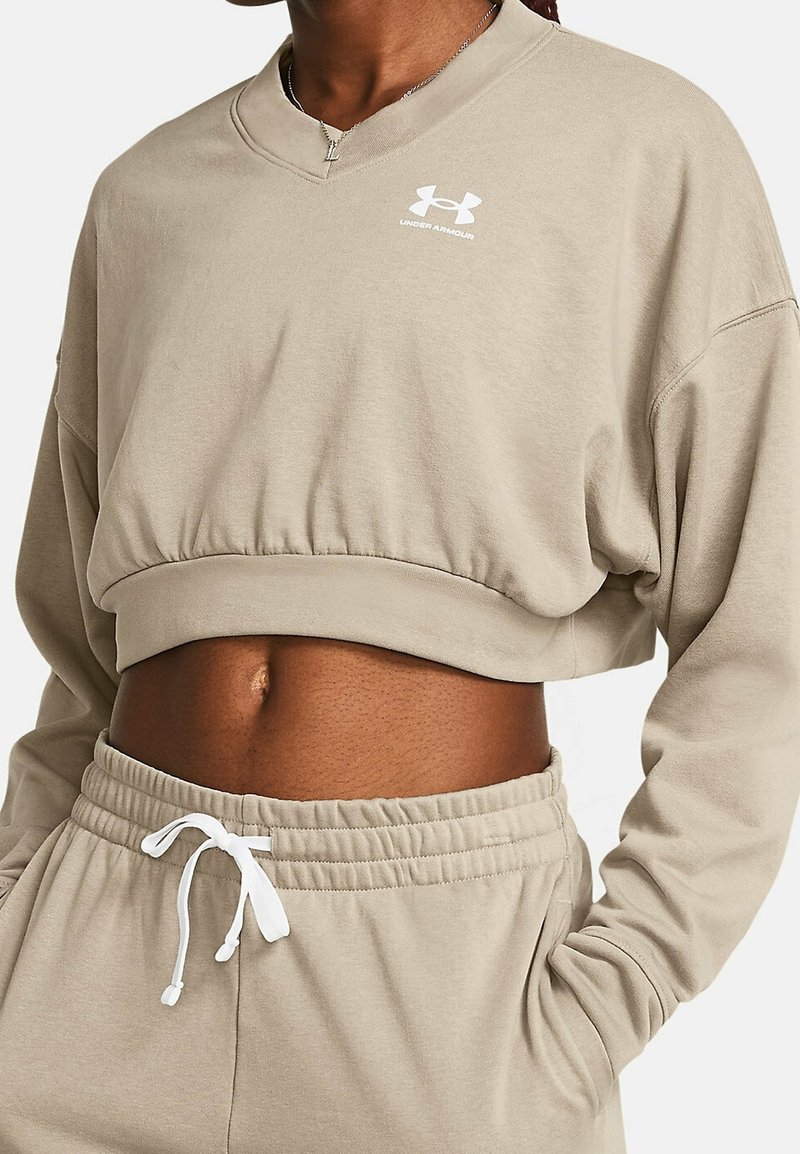 Béžová zkrácená mikina s dlouhými rukávy a výstřihem do V. Obsahuje elastický pás a bílou šňůrku, s malým bílým logem na hrudi.