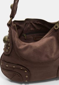 Braune Canvas-Handtasche mit Messingnägeln, einem Reißverschluss-Innenfach und einer weichen, runden Form. Enthält einen kurzen Tragegurt.