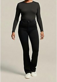 Haut noir à manches longues associé à un jean noir taille haute. La tenue présente une silhouette ajustée et est portée avec des chaussures blanches. Design simple, sans motifs.