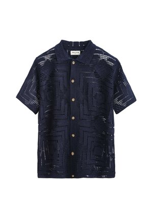 Chemise bleu marine à manches courtes boutonnée avec motif géométrique en maille ajourée et boutons marron clair, avec col et étiquette de marque à l'intérieur.