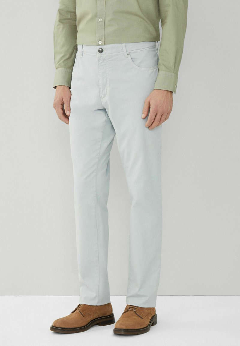 Helle blaue Baumwollhosen mit slim fit, ausgestattet mit Fronttaschen, einem Knopfverschluss und einer glatten Textur, kombiniert mit braunen Wildlederschuhen.