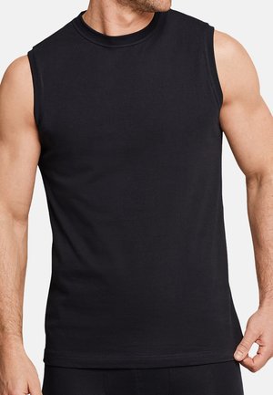 Homme portant un débardeur noir uni, tenant le bord inférieur d'un côté, montrant des bras musclés ainsi qu'une partie du cou et du menton.