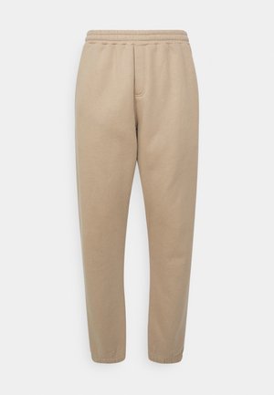 Pantalons de jogging beiges en tissu doux, avec une taille élastique, des jambes fuselées et des poches latérales pour plus de fonctionnalité.