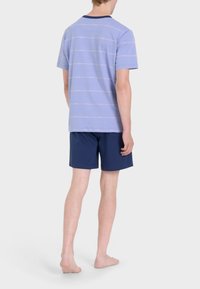 Camicetta a righe lilla a maniche corte con colletto blu navy, abbinata a pantaloni corti blu navy; il tessuto appare morbido, design casual.