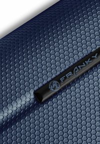 Stylo noir avec le texte « FRANKY » et une icône de globe repose sur une surface bleue à motif hexagonal.