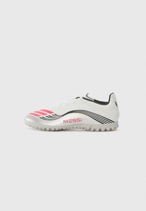 Chaussure de soccer blanche avec des accents argentés, des rayures roses et des motifs ondulés noirs. Dispose d'une semelle texturée pour l'adhérence et de la marque 'MESSi'.