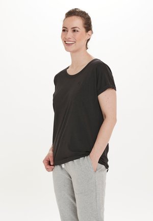 Sort bomulds t-shirt med rund halsudskæring og rullede korte ærmer, båret med lysegrå sweatpants. Enkel design og afslappet pasform.