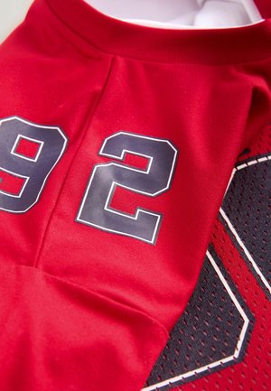 Rød sportstrøje med stort sort og hvidt nummer "92" på glatte og mesh stofsektioner med synlige sømme.