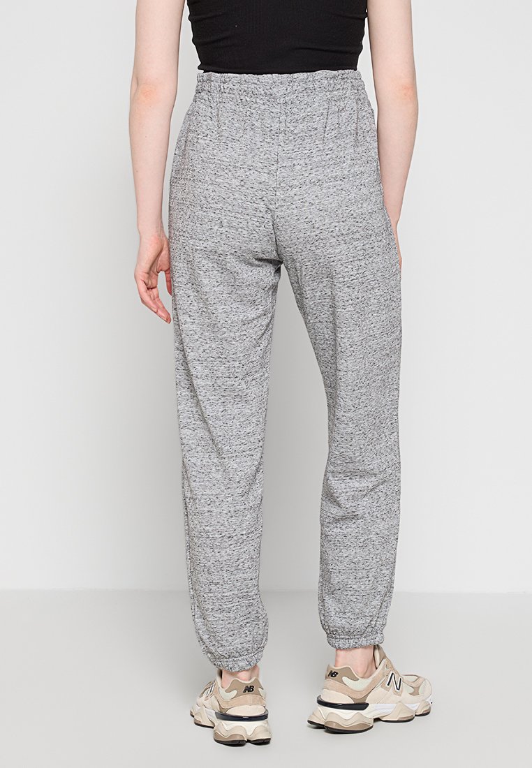 Jogging gris avec une taille élastique et des chevilles resserrées, fabriqué dans un tissu texturé. Assorti à des baskets beiges.