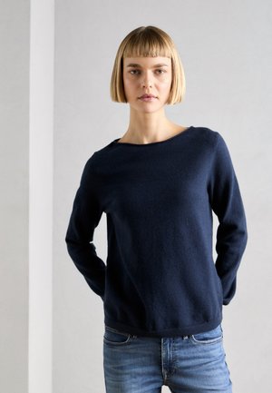 Marineblå, langermet genser med rund hals, laget av teksturert stoff. Kombinert med lyseblå jeans. Enkel design uten synlige utsmykninger.
