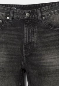 Jean denim noir avec une finition délavée, conception à cinq poches, fermeture à bouton métallique, et coutures tonales présentant de subtiles variations de texture.
