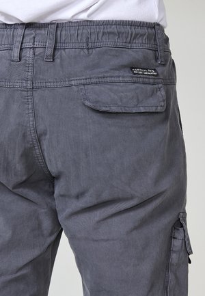 Szürke pamut cargo nadrág rugalmas derékkal, oldalsó zsebekkel és egy hátsó párna zsebbel. Finom texturált felülettel rendelkezik.