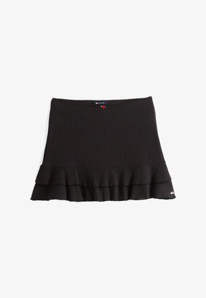 Sort strikkjort med ribbet tekstur, flæsekant og en dekorativ rød accent ved taljen. Har en tætsiddende silhuet.