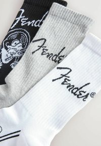 Trei perechi de șosete scurte: negre cu design grafic și logo alb, gri cu logo și albe cu textură ribbed neagră și logo.