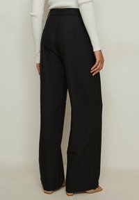 Zwarte wijde broek van een soepele stof, met een aansluitende taille en een minimalistisch ontwerp. Plissé's benadrukken de getailleerde look.